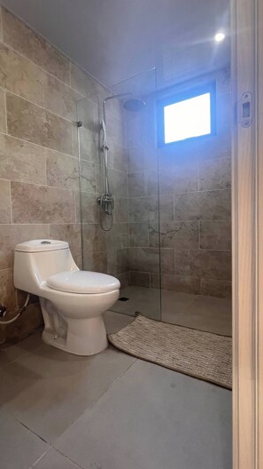 Ein Badezimmer mit Toilette, Dusche und einem kleinen Fenster.