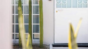 Een witte deur met een decoratief glasraam, een keypad-slot en een klein brievenbusje erboven.