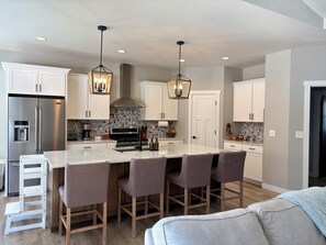 A modern kitchen with a central island, stainless steel appliances, and pendant lighting. - Entire home in the country for EAA, Oshkosh, WI (Van Dyne)