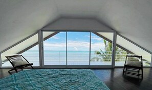 A room with a large window, a bed, and two chairs.