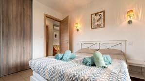 Ein Schlafzimmer mit einem Bett, zwei Wandlampen, einer Tür und einem gerahmten Bild an der Wand.