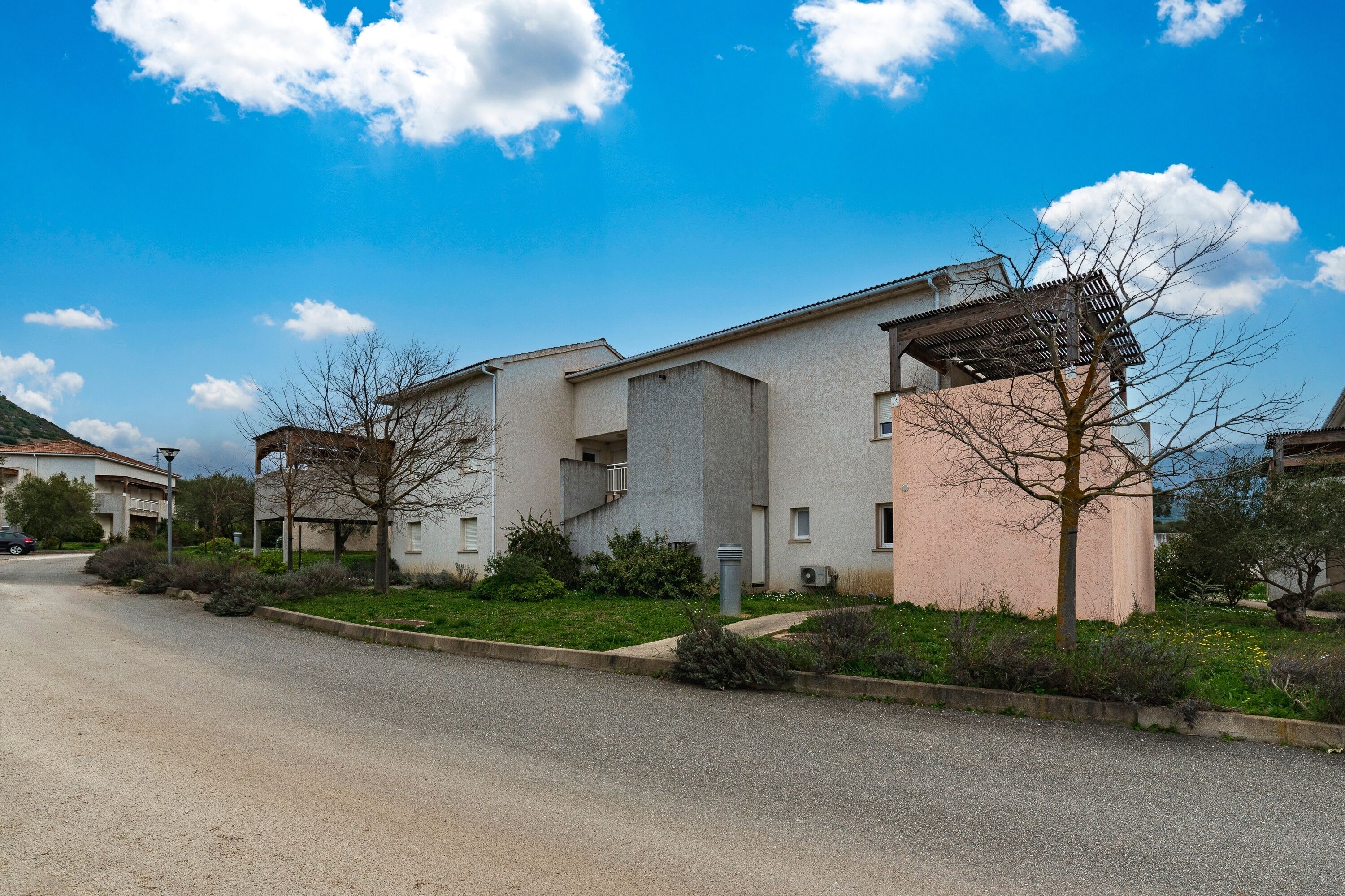 A residential area with modern buildings, a clear sky, and a road.