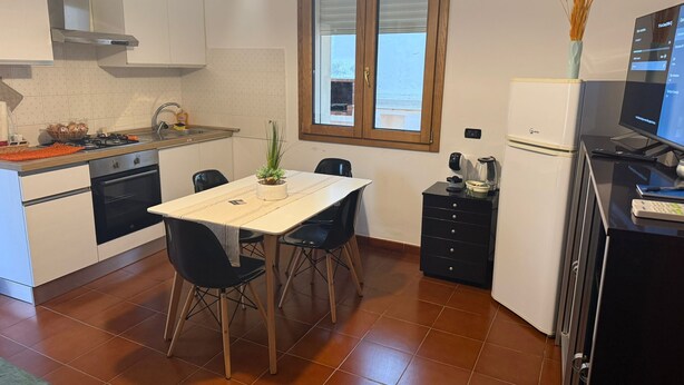Una cuina compacta amb zona de menjador, fogó, forn i nevera.