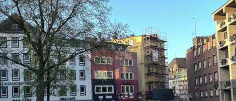 A cobblestone square with buildings, including a cafe and a building under construction.