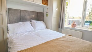 A bed with white bedding, a grey headboard, and a woven throw blanket. - Farnham Park Apartment (Farnham)