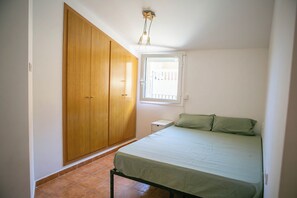 A bedroom with a bed, a wardrobe, a window, and a ceiling light fixture. - 2 bedroom apartment in the center of Begur (H08) (Begur)