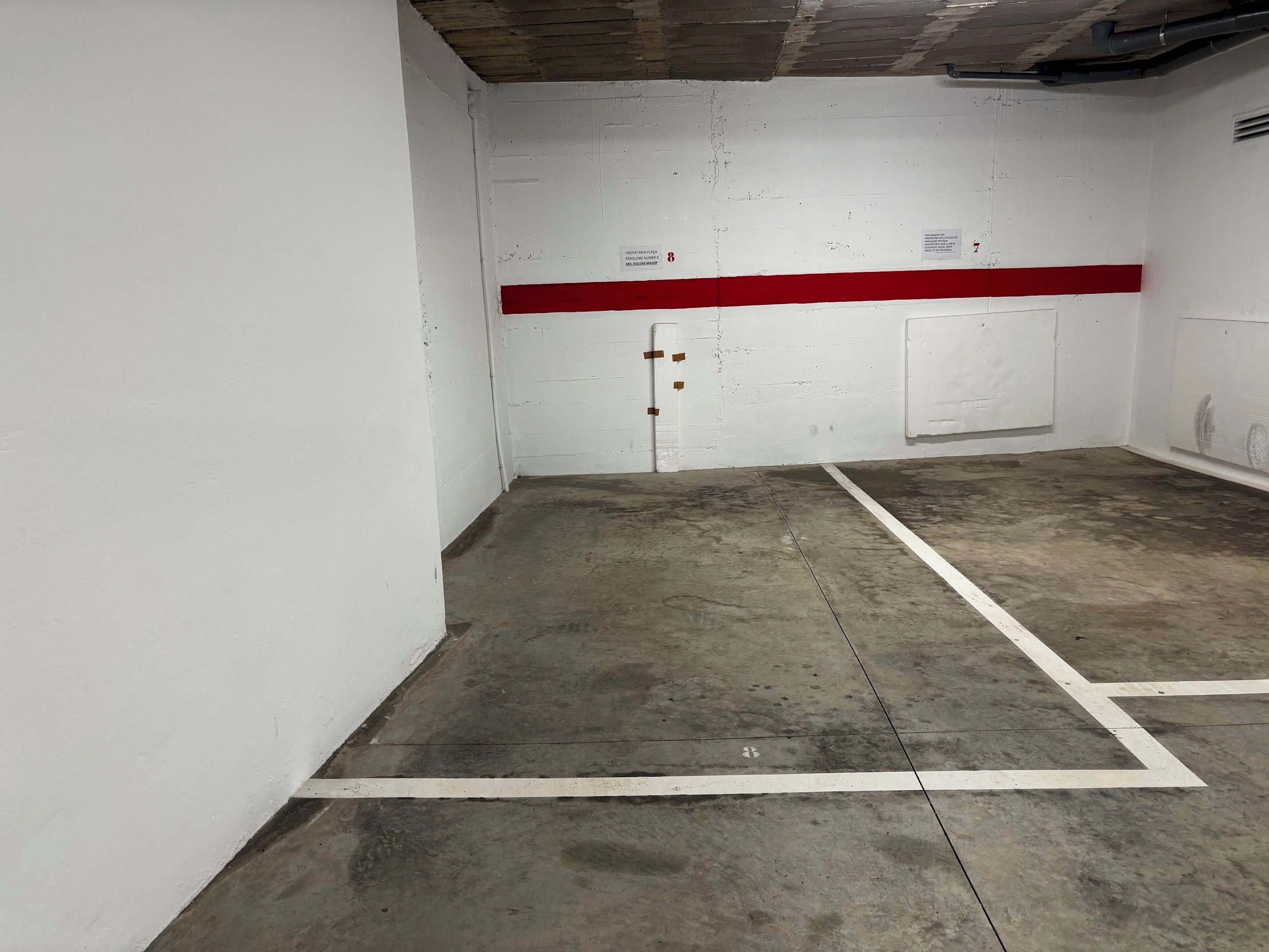 Ett parkeringsgarage med vita väggar, rött och vitt målade linjer och betonggolv.