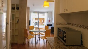 A kitchen with a microwave, a dining table with chairs, and a hanging light fixture. - 2 bedroom apartment in the center of Begur (H08) (Begur)