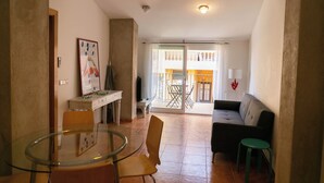 A living room with a sofa, a glass table, and chairs, a balcony with a view, and a dining area with a table and chairs. - 2 bedroom apartment in the center of Begur (H08) (Begur)