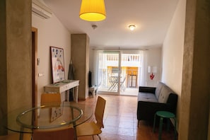 A living room with a sofa, a glass table, and chairs, a balcony with a view, and a dining area with a table and chairs. - 2 bedroom apartment in the center of Begur (H08) (Begur)