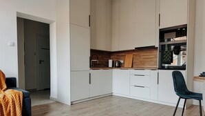 Una cocina moderna con armarios blancos, una encimera de madera y una silla negra.