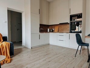 A modern kitchen with white cabinets, a wooden countertop, and a black chair. - Old Town Residence next to Main Station Dapartments.eu (Kraków)