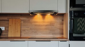 Eine Küche mit eingebauter Mikrowelle, einem Holzschnittbrett und einer Edelstahl-Dunstabzugshaube.