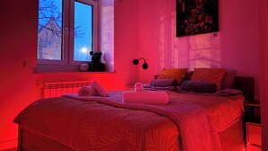 Ein Schlafzimmer mit einem großen Bett, einem Fenster, einer Heizung und einem Wandbild.