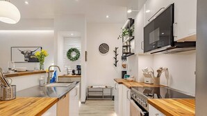 A modern kitchen with wooden countertops, stainless steel appliances, a built-in oven, and a television above the stove.