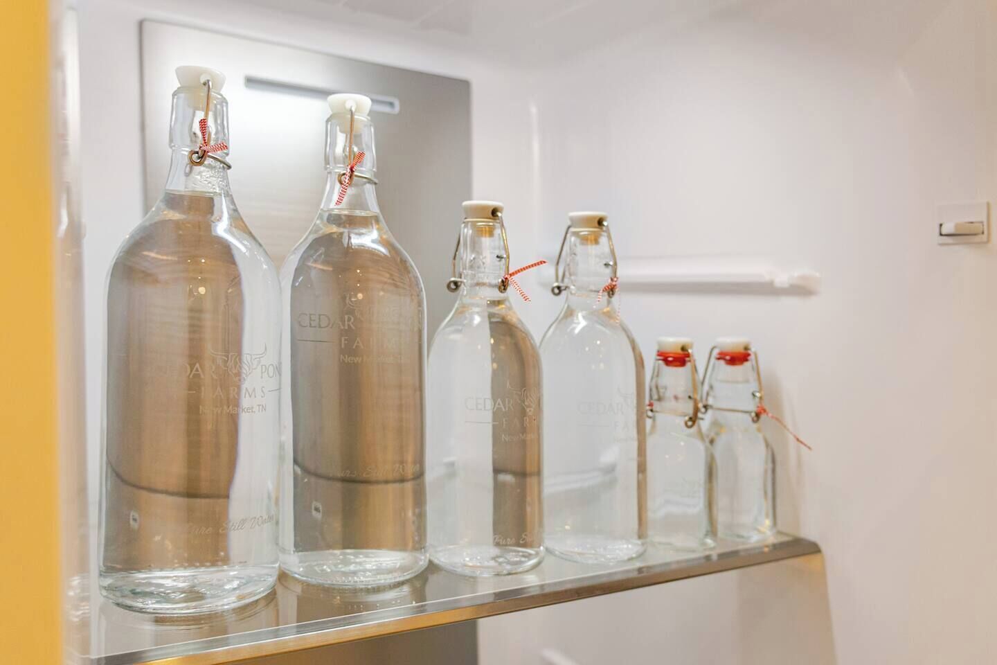 Une rangée de bouteilles en verre, toutes étiquetées, est posée sur une étagère.