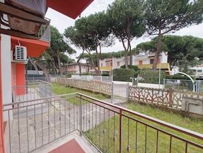 A residential area with a red building, a gated entrance, and surrounding trees. - Welcoming Apartment for Five Guests in Rosolina (Rosolina)