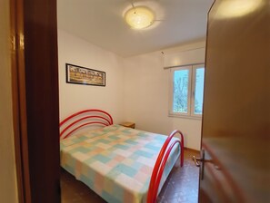 A bedroom with a bed, a window, a door, and a ceiling light. - Nice Flat in Rosolina Mare (Rosolina)