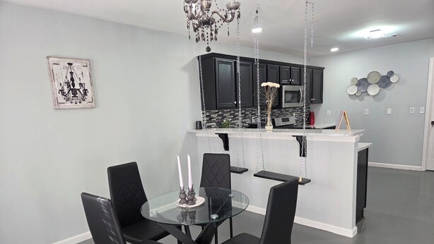 A modern kitchen with black cabinets, a glass island, and a chandelier.