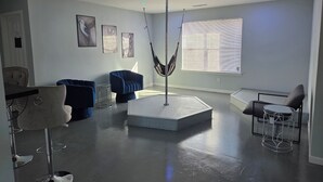 A modern living room with a central seating area, a hammock, and a dining area with a chair and table.