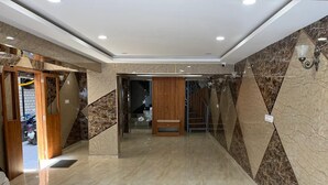 Eine Hotelhalle mit Marmorboden, Holztüren und einer Treppe.