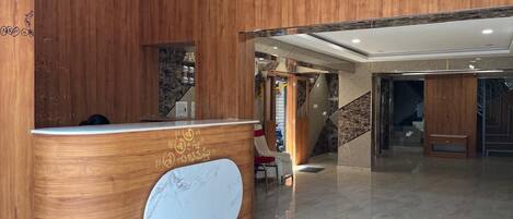 A reception desk with a marble inlay, wooden paneling, and a staircase leading to an upper level.