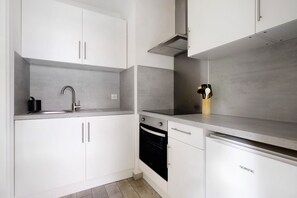 Eine moderne Küche mit weißen Schränken, einer Edelstahl-Spüle, einem Backofen und einem Geschirrspüler.