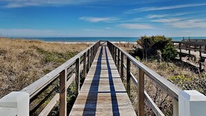 A wooden boardwalk leading to a beach with a clear sky. - Surf's Up (Carolina Beach)