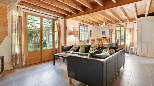 A spacious living area with a sofa, a dining table, and a kitchen in the background.