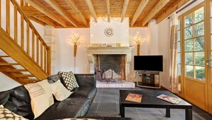 A living room with a fireplace, a sofa, a coffee table, and a TV.