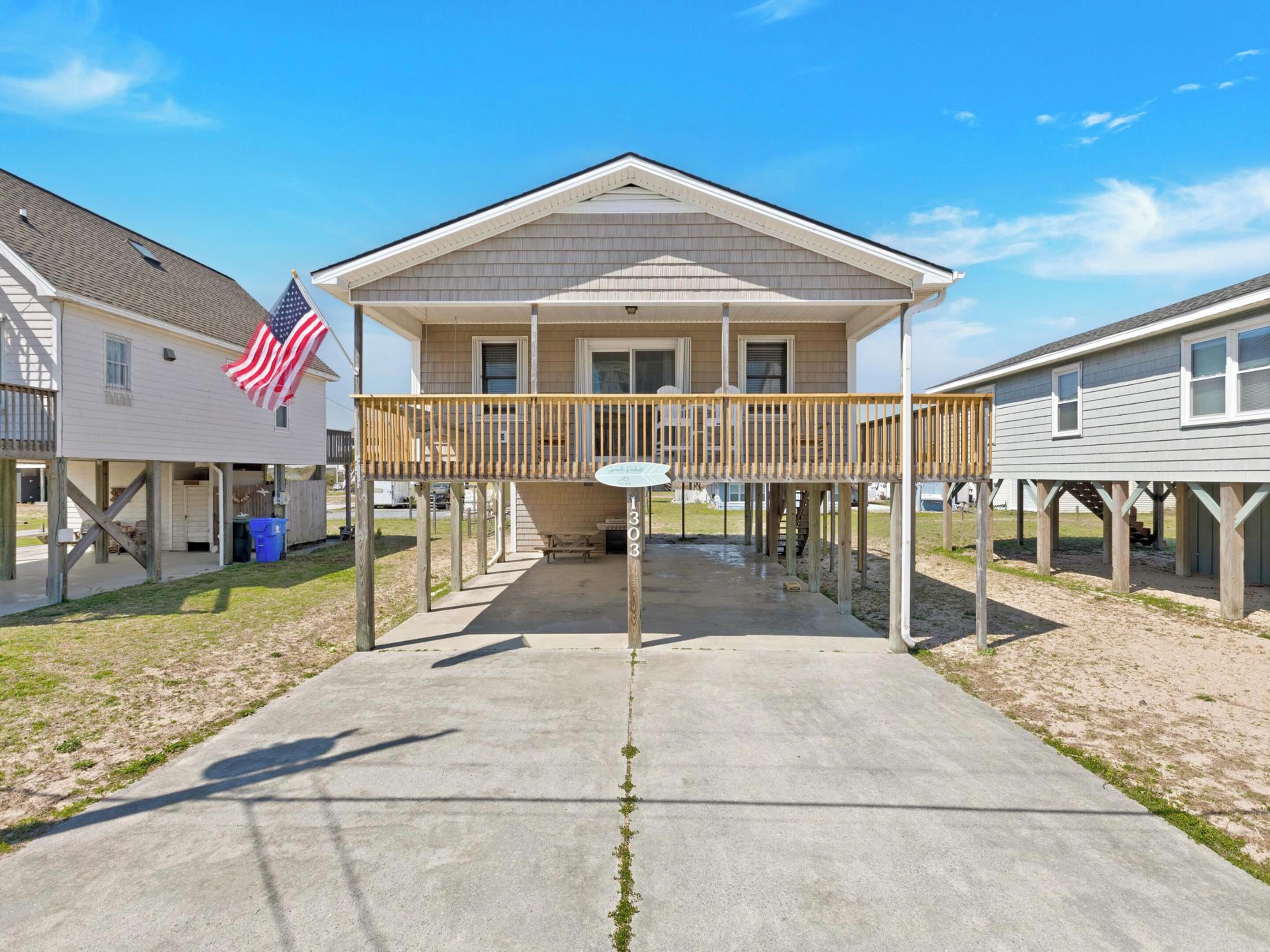 A two-story house with a covered porch and a flag.
