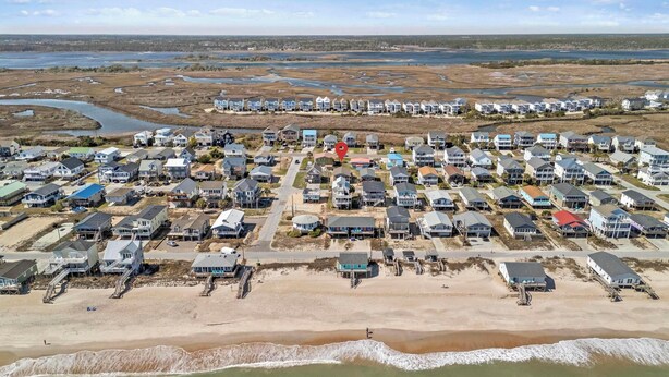 An aerial view of a coastal residential area with houses, a beach, and a marshy landscape. - Spread'n Kindness (Holly Ridge)