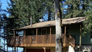 Eine zweistöckige Holzhütte mit Balkon, Garage und Blick auf den umliegenden Wald.