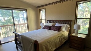 Ein Schlafzimmer mit Bett, Nachttischen und großen Fenstern.