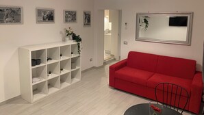 Un salon moderne avec un canapé rouge, une étagère blanche et un miroir.