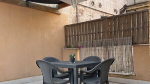 Une terrasse avec une table et des chaises, un luminaire suspendu et une clôture en bois.