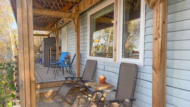 A covered porch with wooden railings, a table, and four chairs.