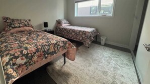 Un dormitorio con dos camas, una ventana y una puerta.