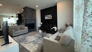 Una sala de estar moderna con chimenea, sofás, una mesa de centro y un televisor.