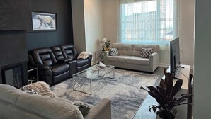 A living room with a fireplace, two sofas, a coffee table, and a large window.
