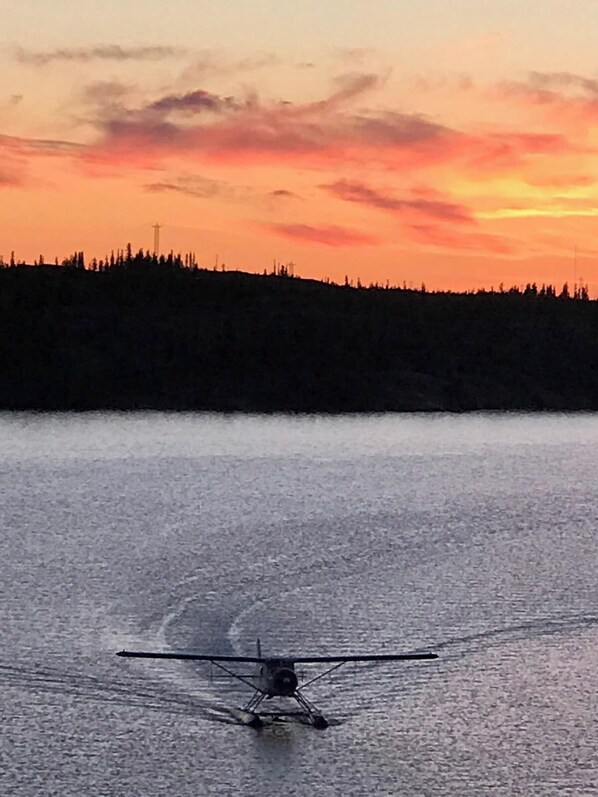 Une étendue d’eau dont le reflet forme la silhouette d’une forêt, avec un petit avion sur l’eau.