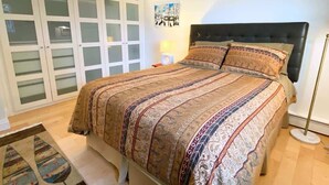 Une chambre à coucher comprenant un lit, une table de chevet, une lampe sur pied et une porte-fenêtre coulissante.