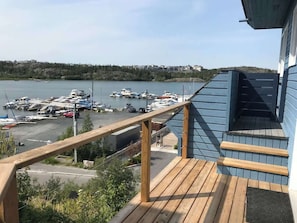 Terraza de madera con vista a un puerto deportivo y barcos.