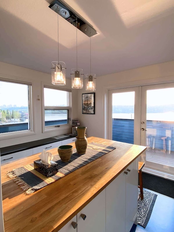 Una cocina moderna con encimera de madera, luces colgantes y vistas al exterior.