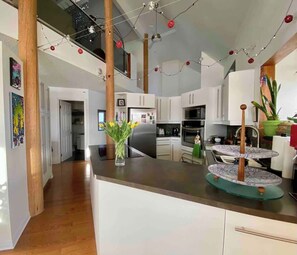 A modern kitchen with white cabinets, a central island, and a dining area with a round table.