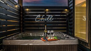 Ein Whirlpool mit einer Weinflasche, Gläsern und Trauben, vor einem Hintergrundschild mit der Aufschrift 'Chill'.