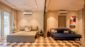 A bedroom with a large bed, a smaller bed, a sofa, and a large window. - Staymaster Solintra 2BHK C101 (Verem)