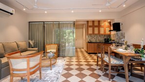Una sala de estar moderna con sofá, sillas, una mesa de comedor y una zona de cocina con armarios y estufa.