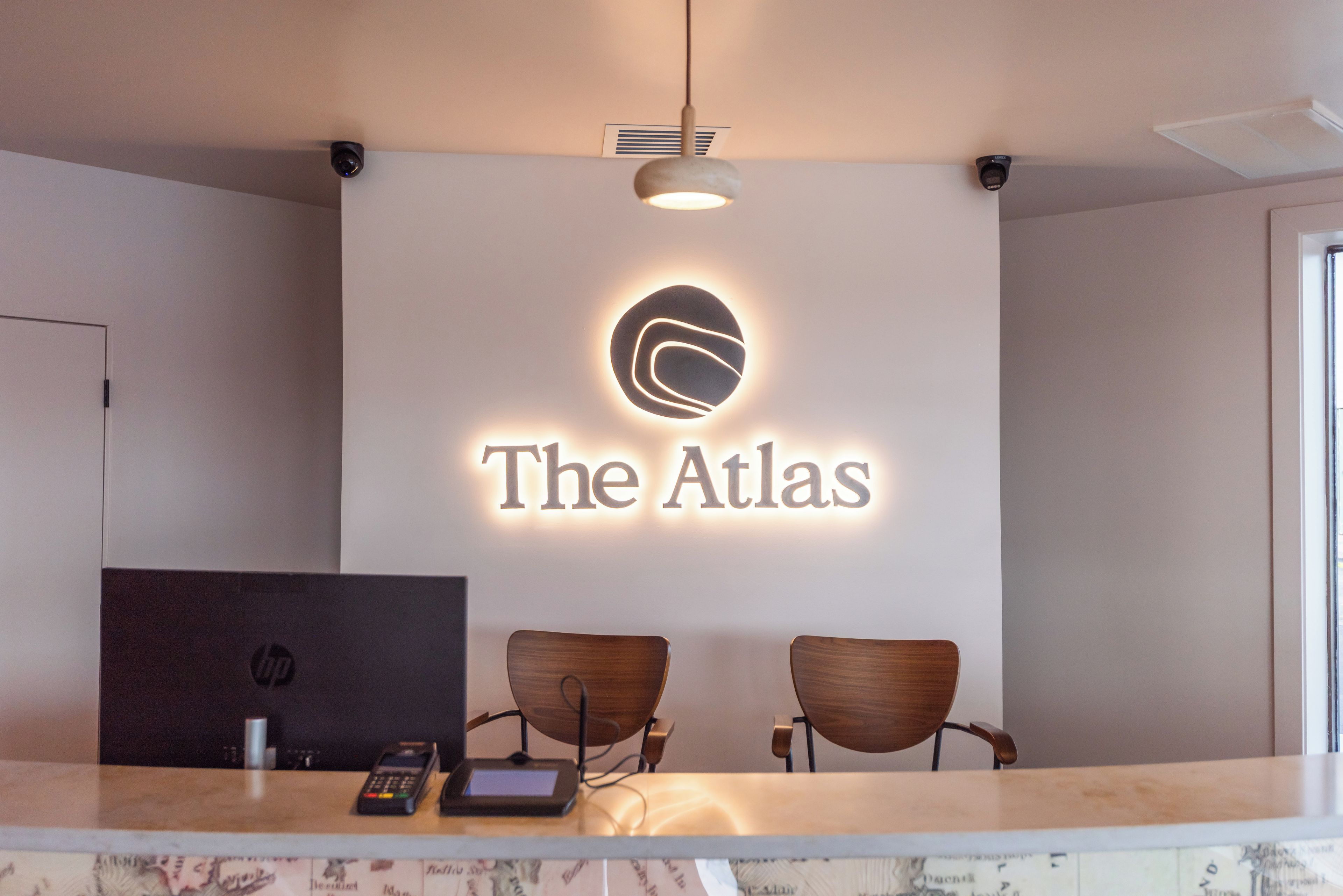 Una mesa de recepción con un cartel que dice 'The Atlas' y dos sillas de madera.
