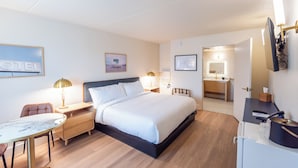 A hotel room with a bed, bedside tables, a desk, a chair, a mirror, and a framed picture on the wall. -  The Atlas Hotel & Lofts (Goodlettsville)